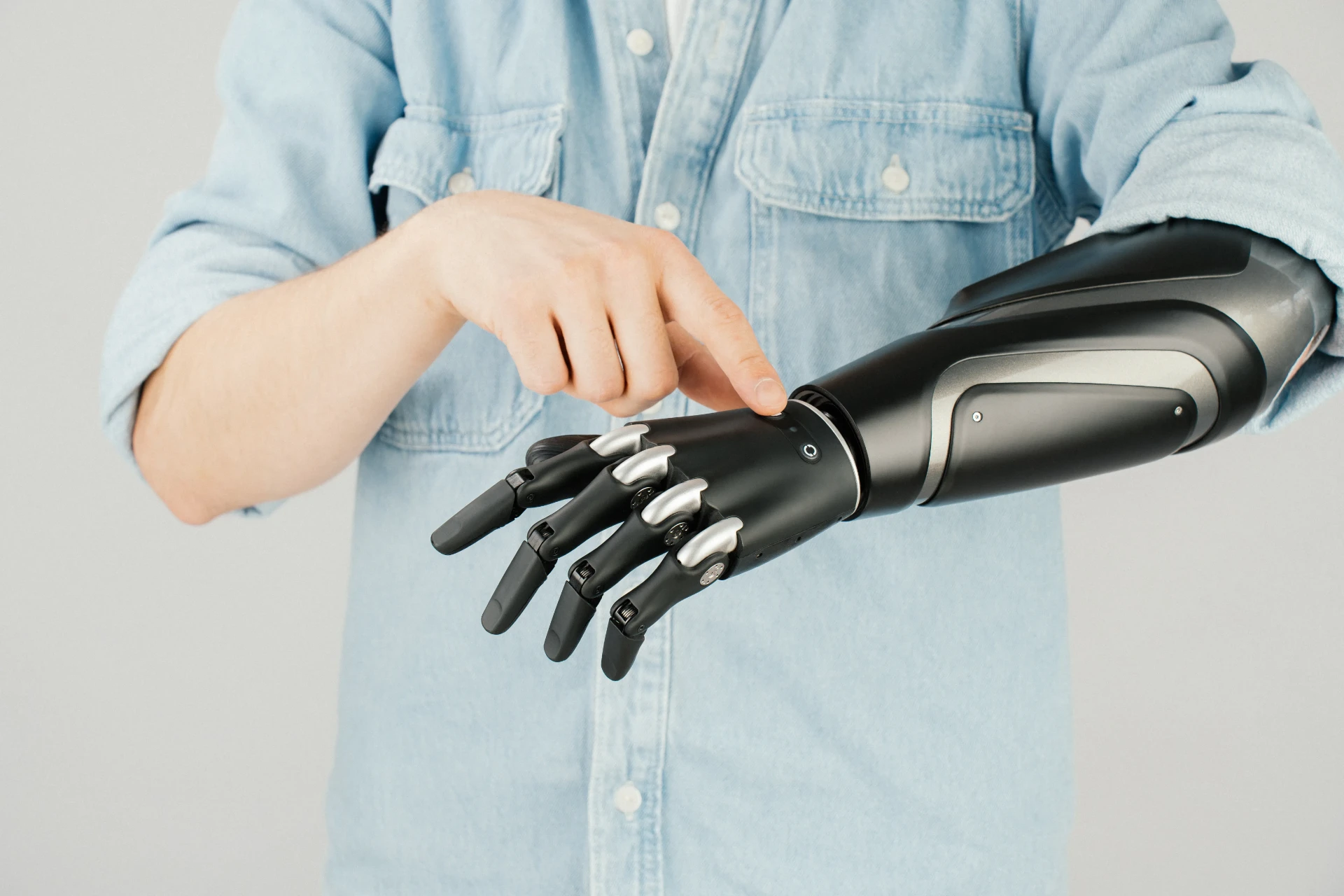Zeus Hand bionic prosthetic arm in matte black and silver worn by a person in a denim shirt